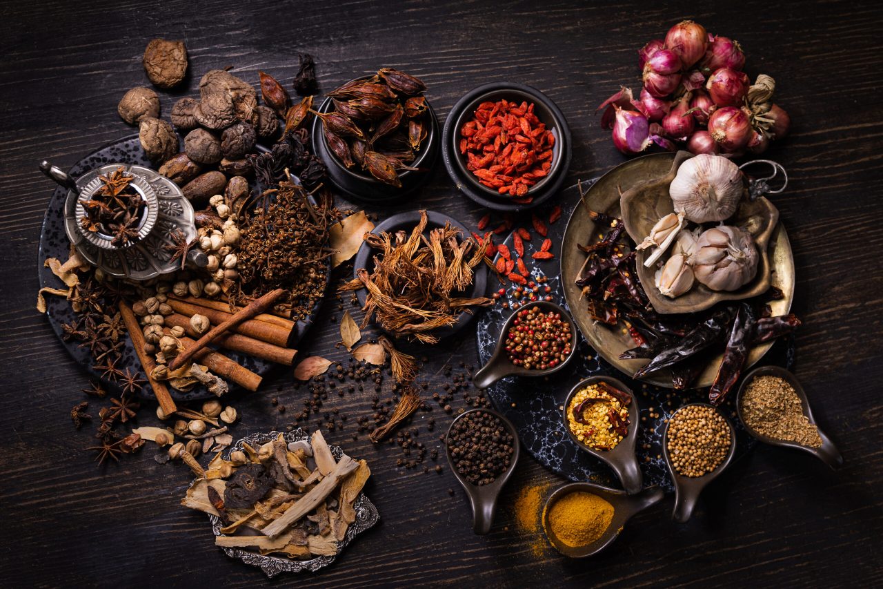 Thai native food, spices herbs, and various ingredients taken from top view angle.  Group of hot and spicy dry vegetables, nuts, and grains for making Asian food on wooden background. Dark tone photo.